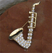 Vintage brooch of saxophone with gold metal and rhinestones. 