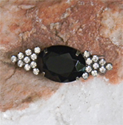 brooch has black glass faceted in oval shape decorated with rhinestones.